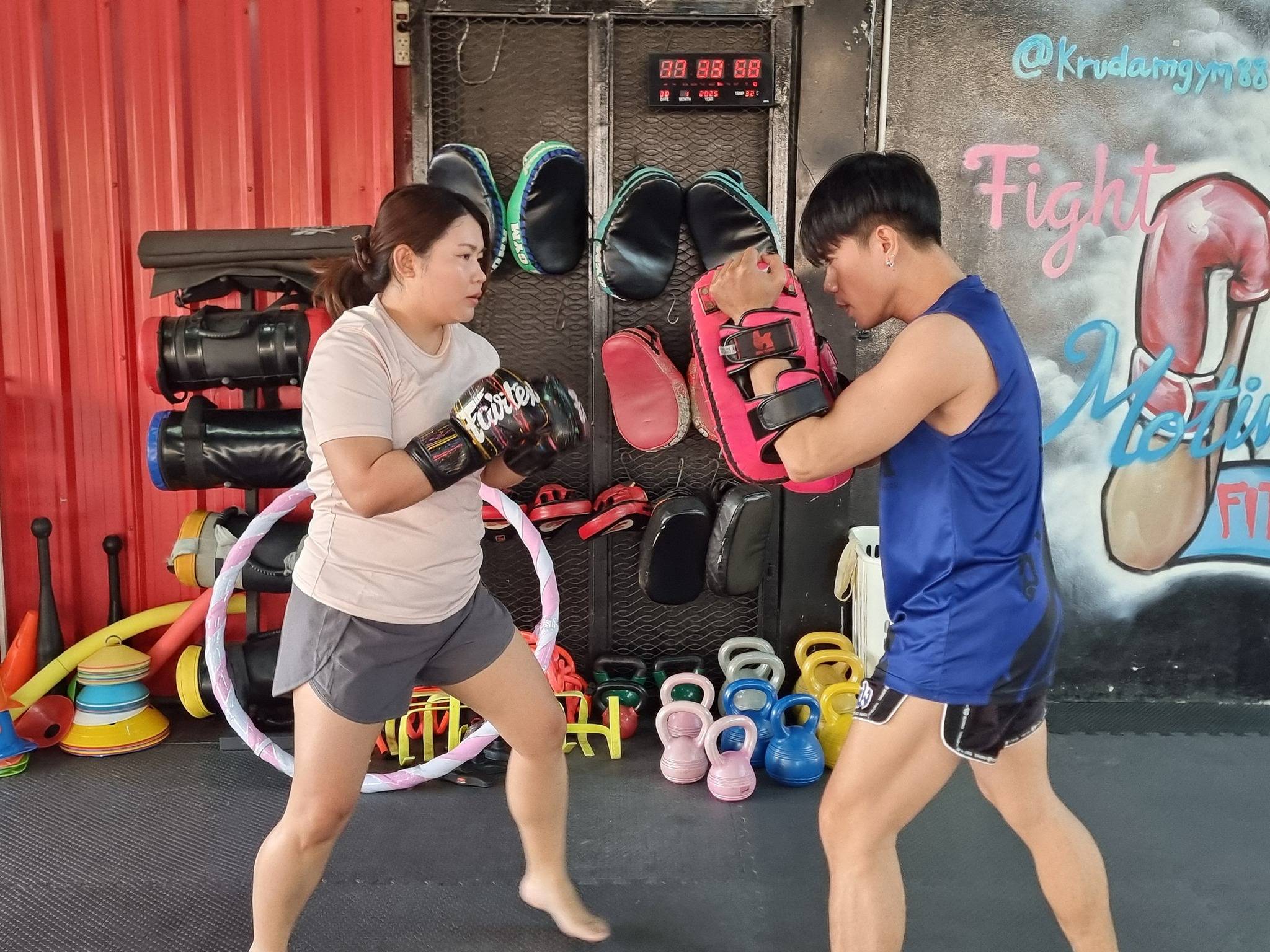 students practicing Muay Thai pad work during a group training session at KruDam Gym Ratburana Bangkok