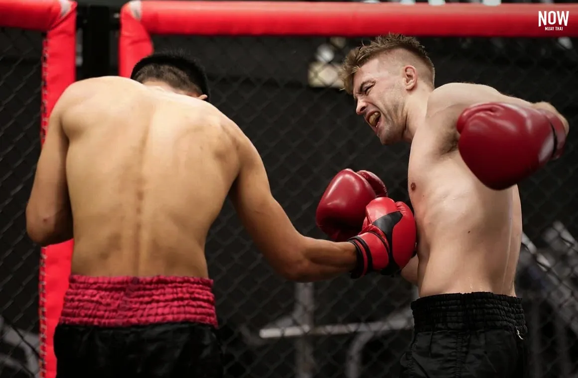  A Muay Mat fighter delivering a powerful body hook punch to his opponent’s ribs using classic Muay Thai punching technique.