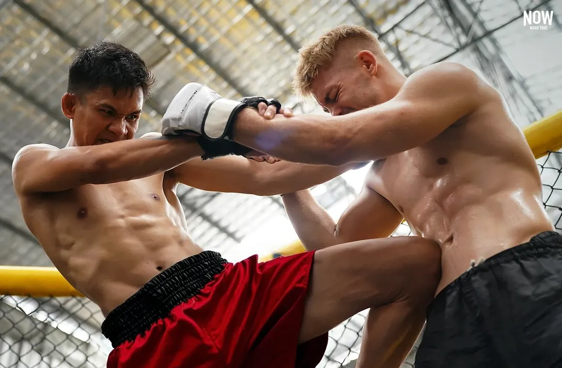 A Muay Khao specialist executing a Spearing Knee (Khao La) to the opponent’s side while clinching in close-range combat.