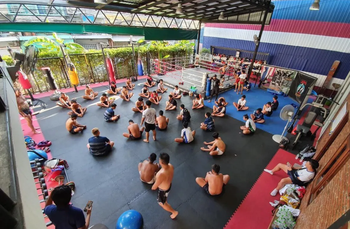 Group of Muay Thai enthusiasts stretching and warming up before class at Rithirit Gym Academy