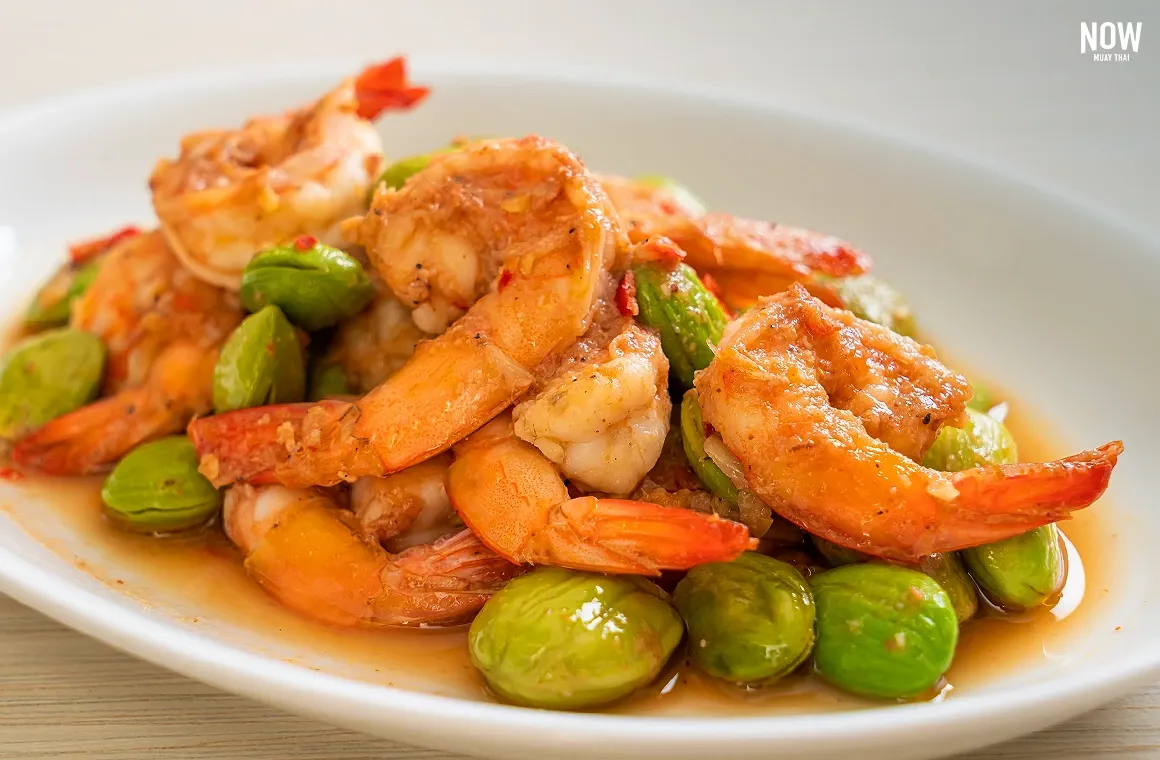 Pad Sataw, a Southern Thai stir-fry of pungent stink beans with shrimp, cooked in spicy shrimp paste and served with fresh vegetables for a flavorful, nutritious dish.
