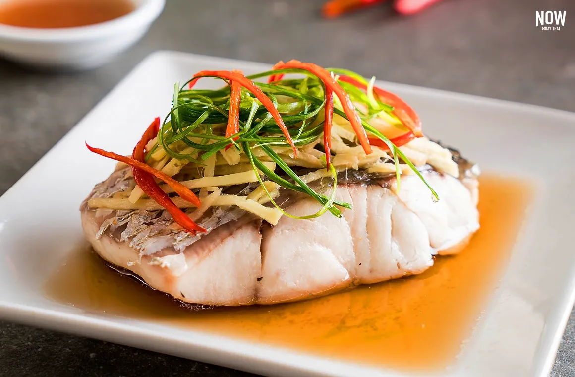 Steamed sea bass in light soy sauce topped with ginger, scallions, and chili, a clean and flavorful dish rich in protein and omega-3s that supports heart health, reduces inflammation, and aids digestion
