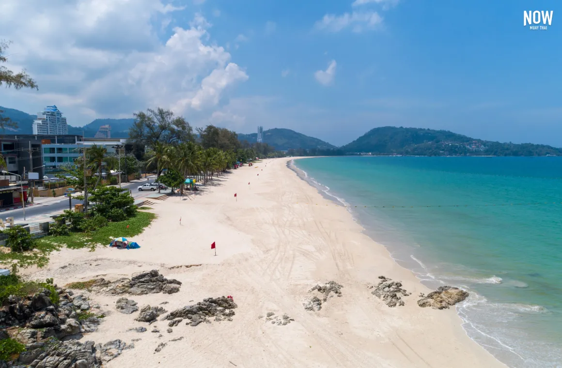 lear, sunny day at Patong Beach in Phuket with soft white sand and turquoise waters, showcasing its beauty as one of the most popular and vibrant beaches for tourists visiting the island