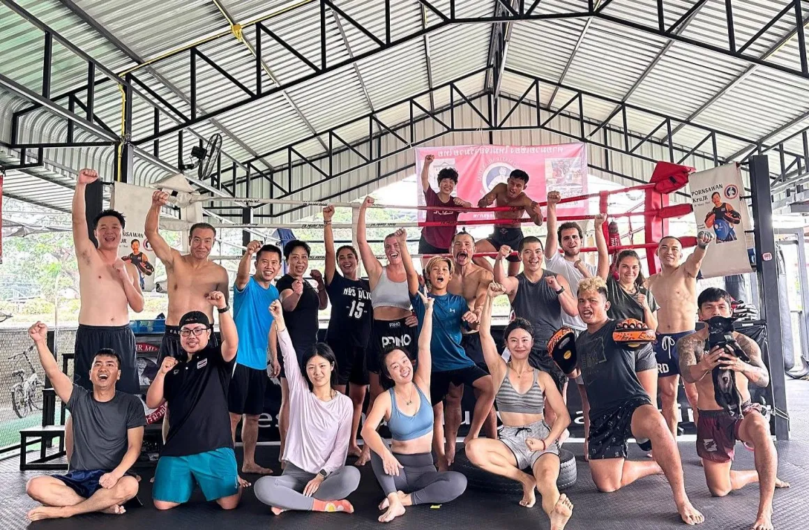 Kru JR celebrating with his students after Muay Thai class at Chiangmai JR Muaythai Gym, posing together for a cheerful group photo in a fun and friendly atmosphere