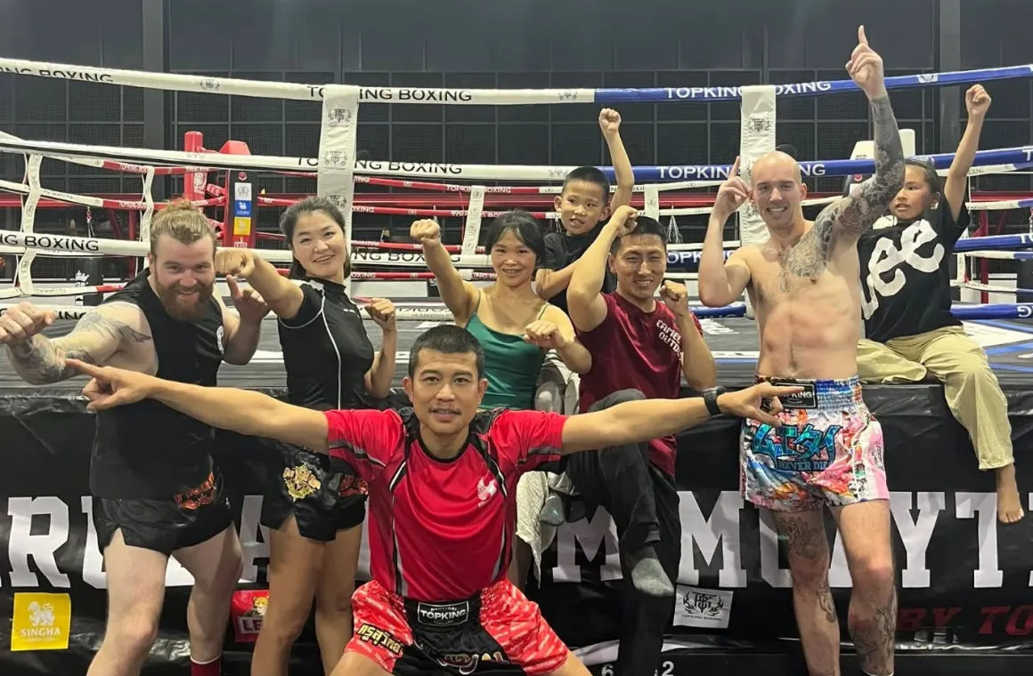 Trainer at Krudam Gym Chiang Mai posing in front of the boxing ring after Muay Thai class, capturing a moment of pride and readiness in a professional training environment